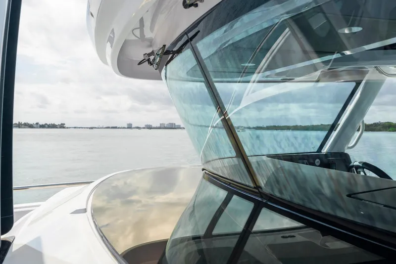 Slide: The Image of 2025 Axopar 45 Cross Top boat with sleek windshield design on calm waters. - 56