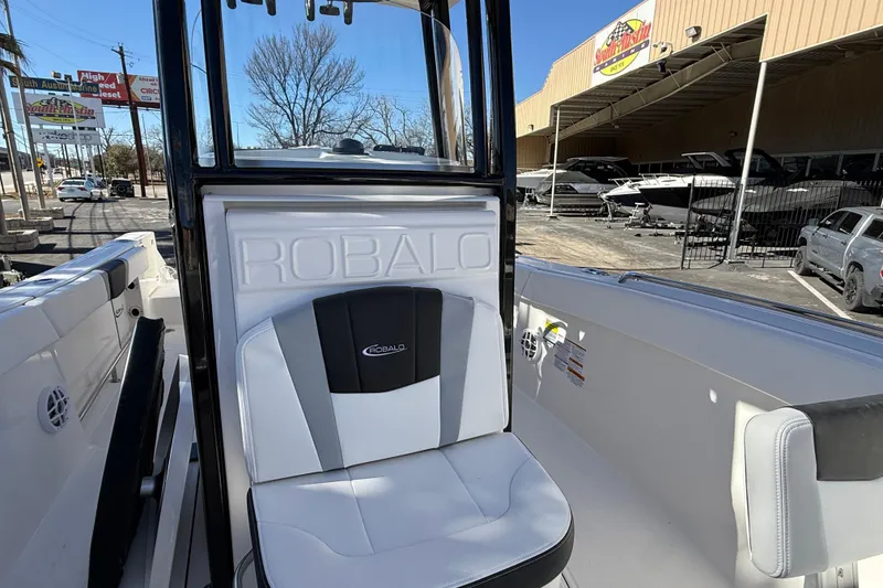 Slide: The Image of 2024 Robalo R230 Center Console boat interior with branded seating and outdoor dealership view. - 55