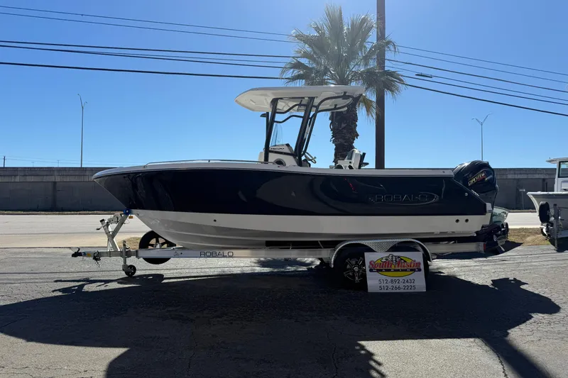 Slide: The Image of 2024 Robalo R230 Center Console boat on trailer, parked outdoors under clear sky. - 57