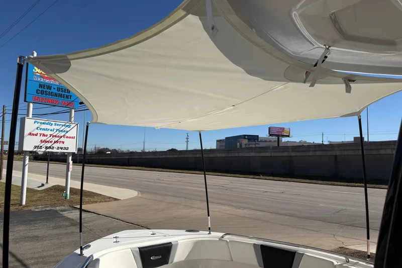 Slide: The Image of 2024 Robalo R230 Center Console boat with sunshade, parked near a consignment sign. - 68