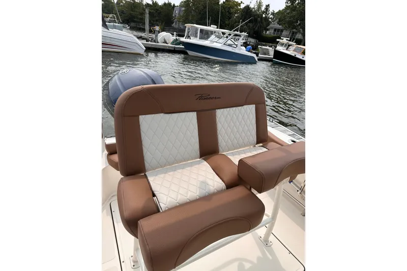 Slide: The Image of 2024 Pioneer 222 Islander boat with brown and white cushioned seating at a marina. - 10