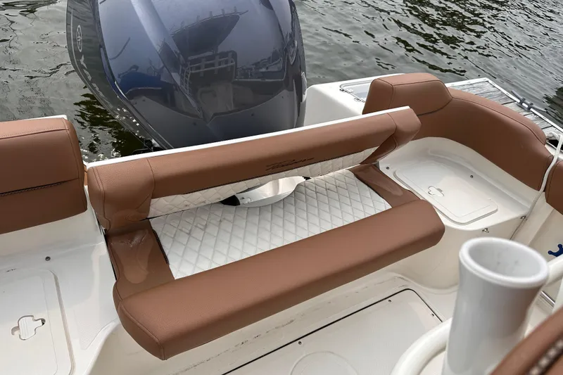 Slide: The Image of 2024 Pioneer 222 Islander boat with brown seating and outboard motor, docked on water. - 12