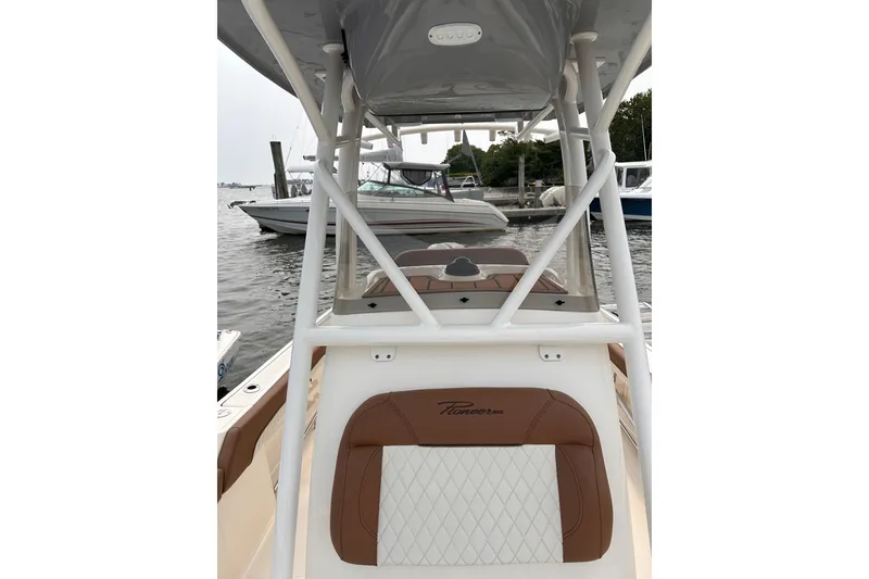 Slide: The Image of 2024 Pioneer 222 Islander boat interior with brown and white seating, docked at marina. - 4