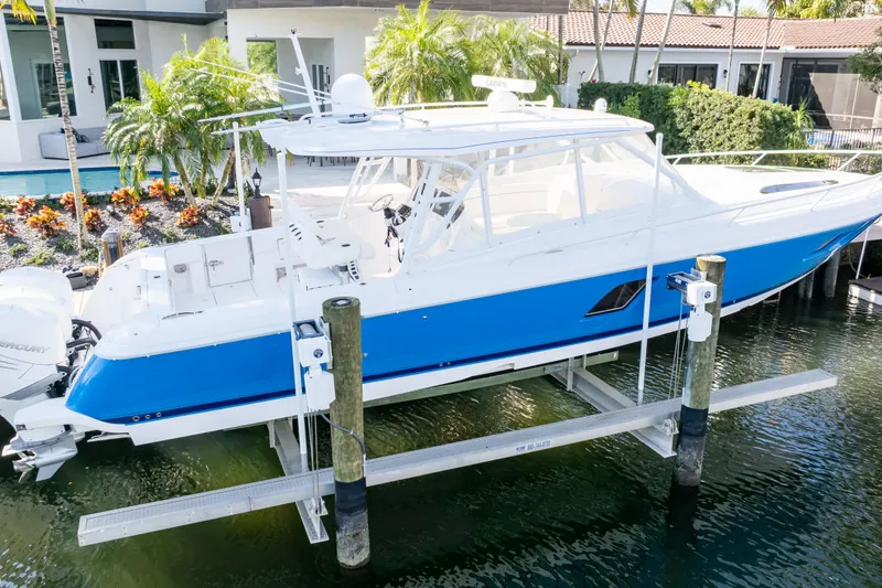 The Image of 2019 Intrepid 407 Cuddy boat docked, featuring sleek blue and white design. - 0