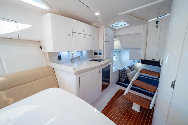 Slide: The Image of 2019 Intrepid 407 Cuddy interior with modern kitchen, seating, and wooden steps. - 10