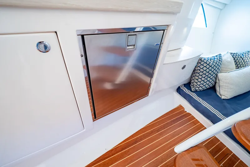 Slide: The Image of Interior of 2019 Intrepid 407 Cuddy with stainless steel fridge and cushioned seating. - 115