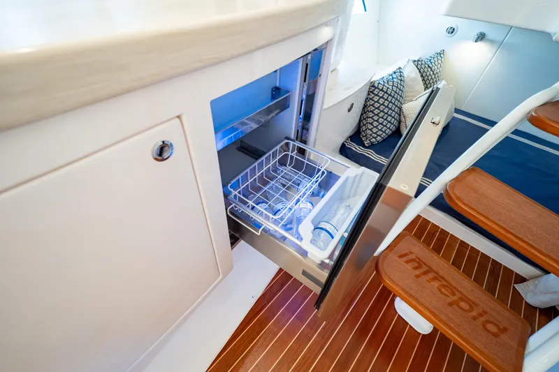 Slide: The Image of 2019 Intrepid 407 Cuddy interior with open fridge, wooden steps, and cushions. - 116