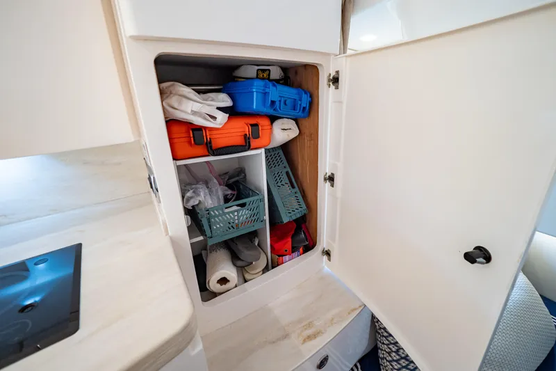 Slide: The Image of Storage cabinet on 2019 Intrepid 407 Cuddy boat, containing various supplies and equipment. - 117
