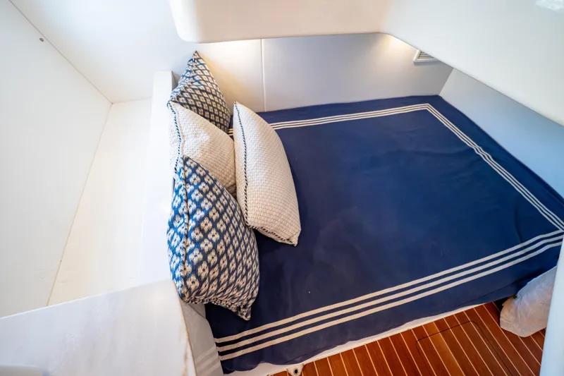 Slide: The Image of 2019 Intrepid 407 Cuddy cabin with blue bedding and patterned pillows. - 12