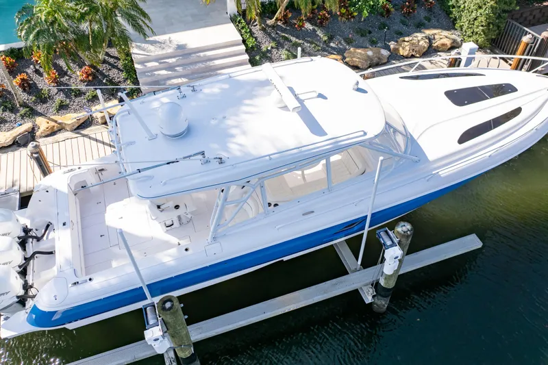 Slide: The Image of 2019 Intrepid 407 Cuddy boat docked, aerial view, surrounded by lush greenery. - 13