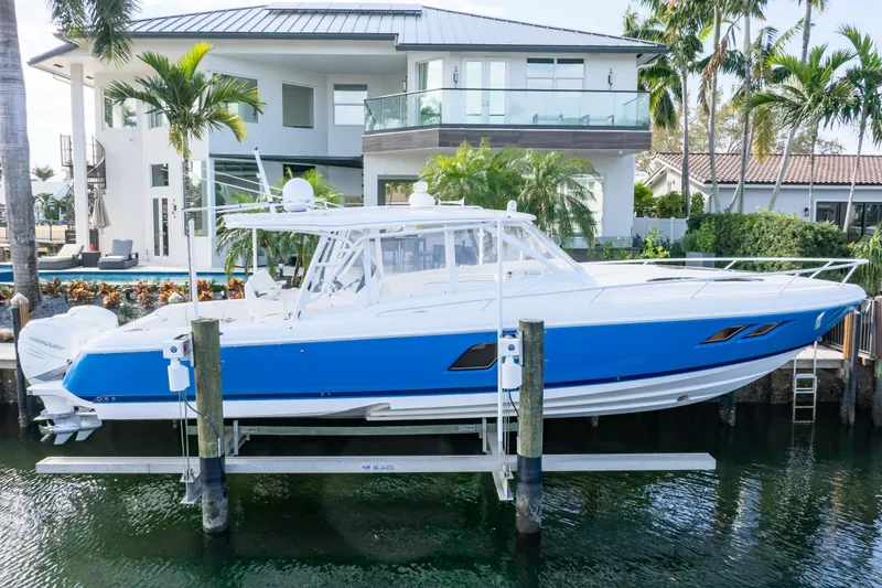 Slide: The Image of 2019 Intrepid 407 Cuddy boat docked near a modern waterfront home. - 14