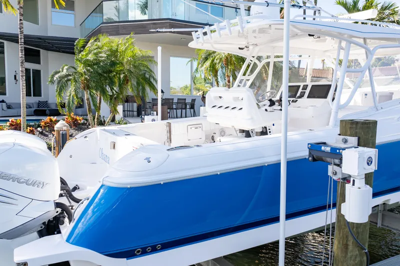 Slide: The Image of 2019 Intrepid 407 Cuddy boat docked near a modern waterfront home. - 15