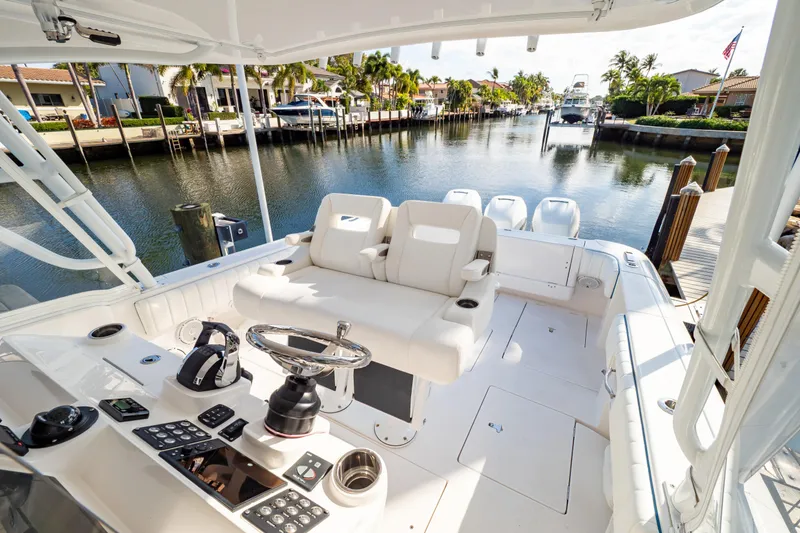 Slide: The Image of 2019 Intrepid 407 Cuddy boat interior with helm, seating, and canal view. - 2