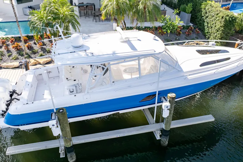 Slide: The Image of 2019 Intrepid 407 Cuddy boat docked, featuring sleek design and vibrant blue hull. - 23
