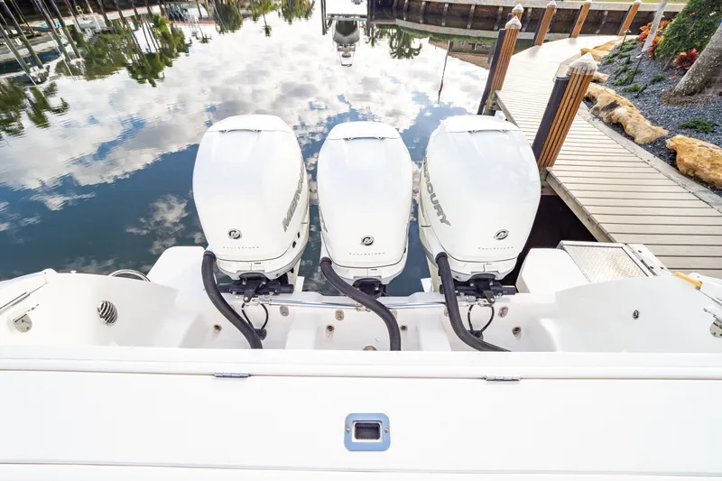 Slide: The Image of Triple Mercury outboard engines on a 2019 Intrepid 407 Cuddy boat docked by a wooden pier. - 25