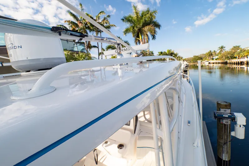 Slide: The Image of 2019 Intrepid 407 Cuddy boat docked by a serene waterfront with palm trees. - 45
