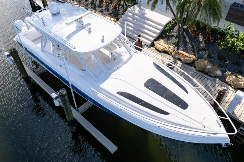Slide: The Image of 2019 Intrepid 407 Cuddy boat docked by a tropical garden. - 5