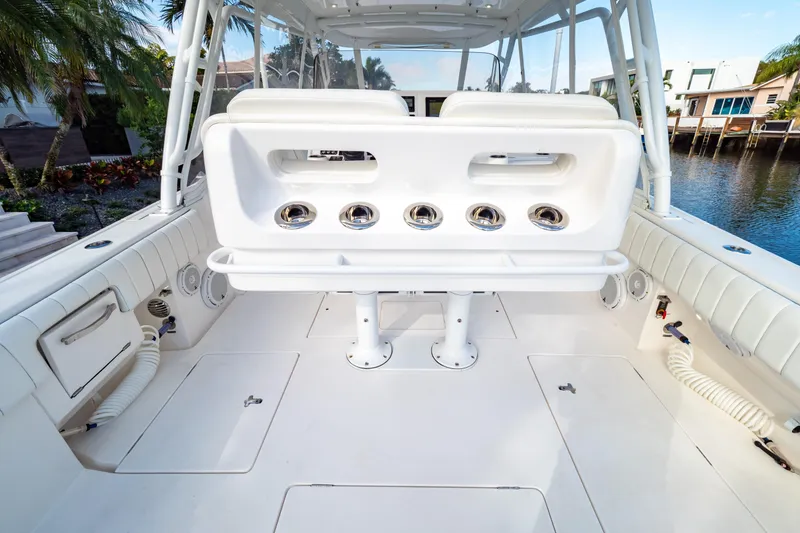 Slide: The Image of 2019 Intrepid 407 Cuddy boat interior with seating and rod holders, docked by waterfront homes. - 53