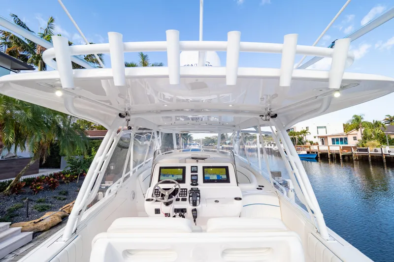 Slide: The Image of 2019 Intrepid 407 Cuddy boat interior with advanced navigation system, docked by a scenic waterfront. - 54