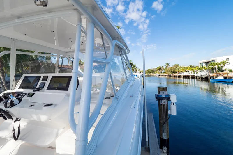 Slide: The Image of 2019 Intrepid 407 Cuddy boat docked by a scenic waterfront under a clear blue sky. - 69