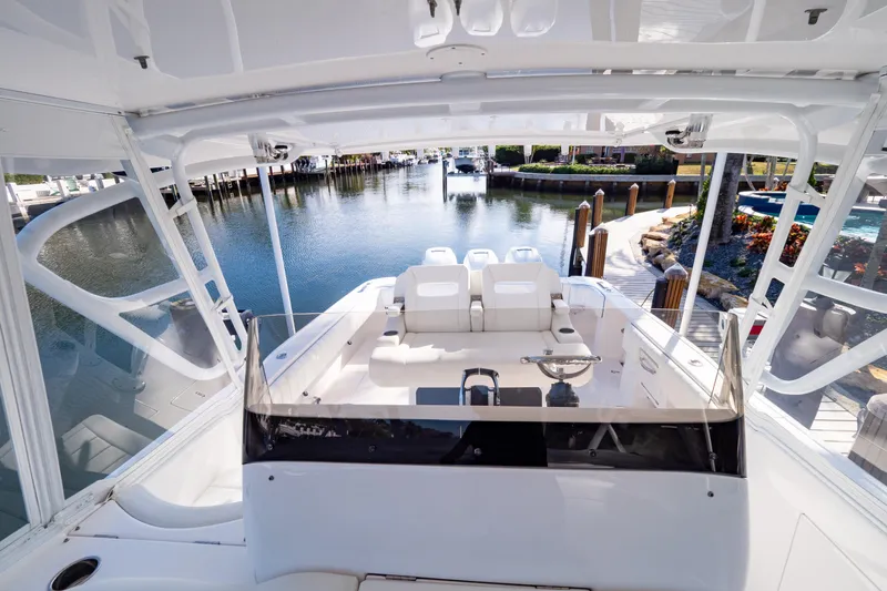 Slide: The Image of 2019 Intrepid 407 Cuddy boat interior with seating, docked by a scenic waterfront. - 76