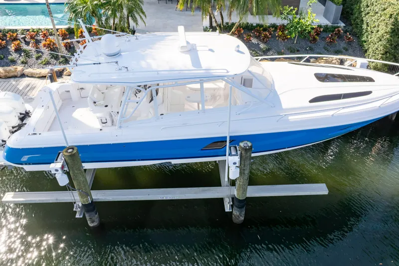 Slide: The Image of 2019 Intrepid 407 Cuddy boat on lift, blue and white design, dockside view. - 8