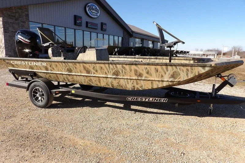The Image of 2026 Crestliner 1860 Retriever SC boat with camouflage design on a trailer outside a marine center. - 1