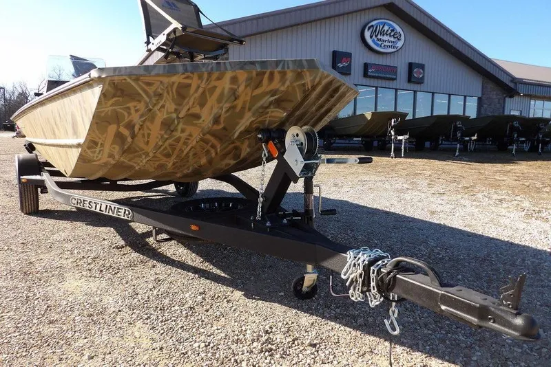 Slide: The Image of 2026 Crestliner 1860 Retriever SC boat on trailer, camo design, outside marine center. - 38