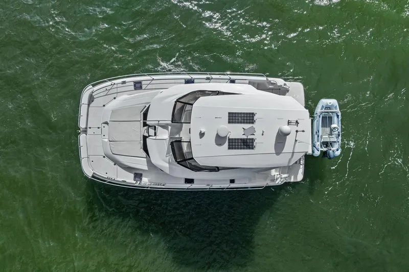 Slide: The Image of Overhead view of 2021 Aquila 44 Yacht with attached small boat on green water. - 10