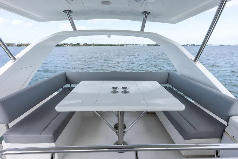 Slide: The Image of Aquila 44 Yacht 2021 interior with sleek seating and table overlooking the water. - 43