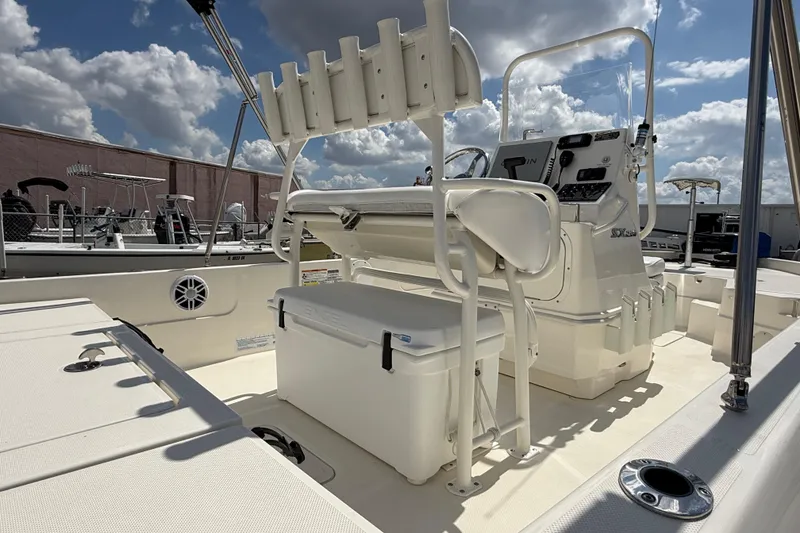 Slide: The Image of 2024 Skeeter SX210 boat interior with console, seating, and rod holders under a cloudy sky. - 12