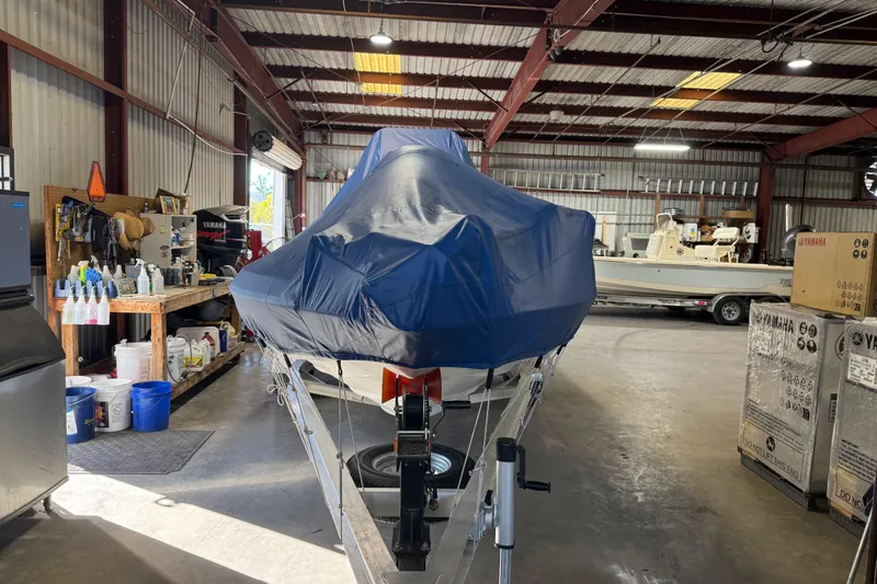 Slide: The Image of 2024 Skeeter SX210 boat covered in a garage with equipment and supplies. - 15