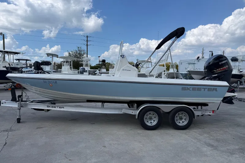 Slide: The Image of 2024 Skeeter SX210 boat on trailer, displayed outdoors under a partly cloudy sky. - 3