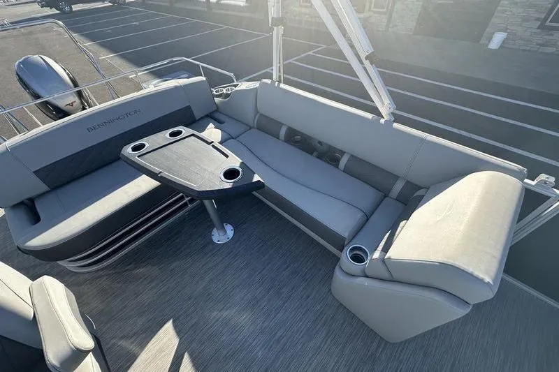 Slide: The Image of 2021 Bennington 23 LSB boat interior with gray seating and table, in a parking lot. - 11