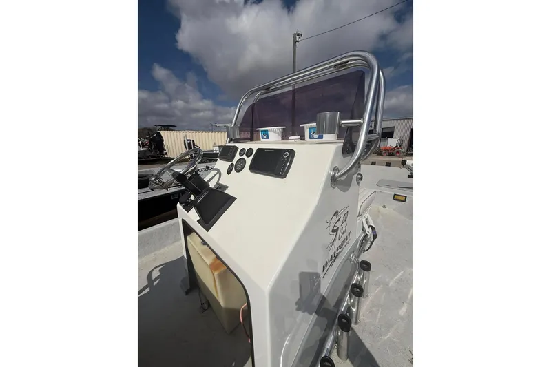 Slide: The Image of 2019 Shoalwater 20 Catamaran boat console with steering wheel and gauges under cloudy sky. - 6