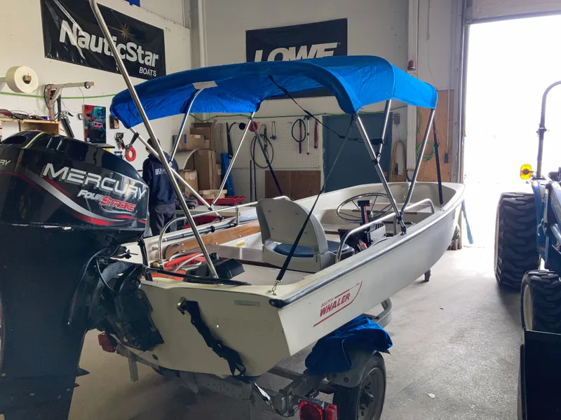 Slide: The Image of 1989 Boston Whaler 13 Sport boat with blue bimini top in workshop. - 7
