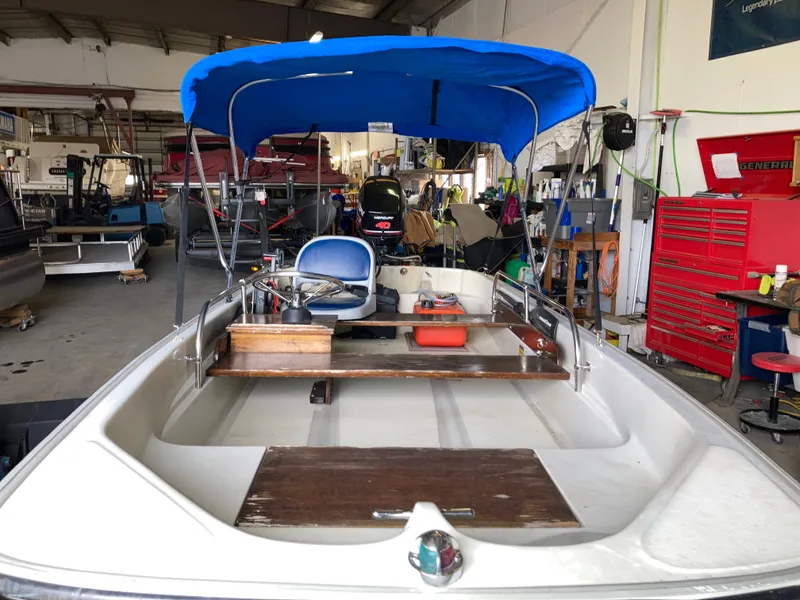 Slide: The Image of 1989 Boston Whaler 13 Sport boat in workshop with blue canopy. - 8