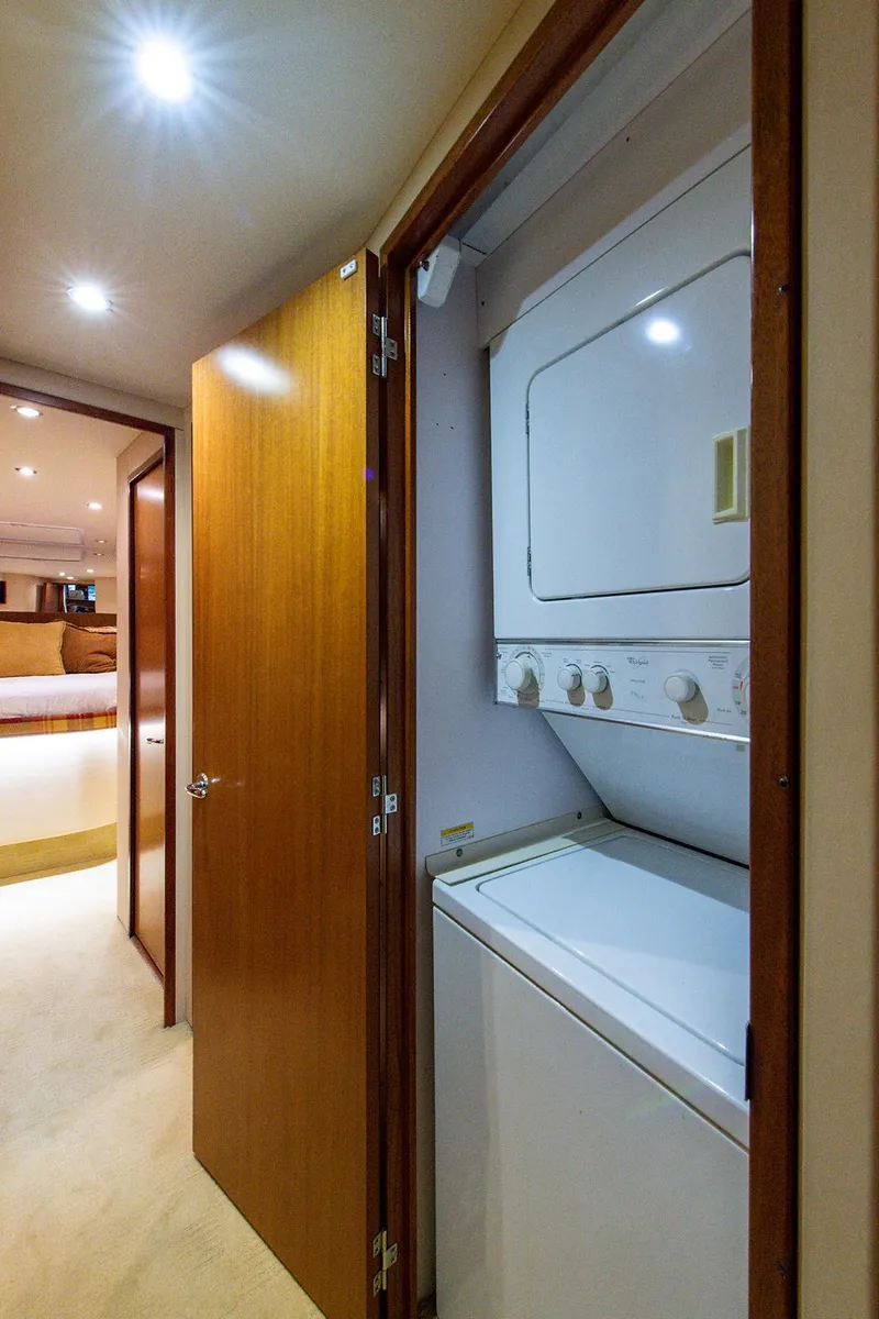 Slide: The Image of Laundry area inside 2006 Hatteras 64 Convertible yacht, featuring a stacked washer and dryer. - 32