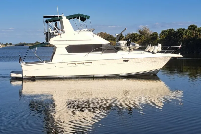 The Image of 2000 Silverton 42 Convertible yacht on calm water, reflecting clear blue sky. - 0