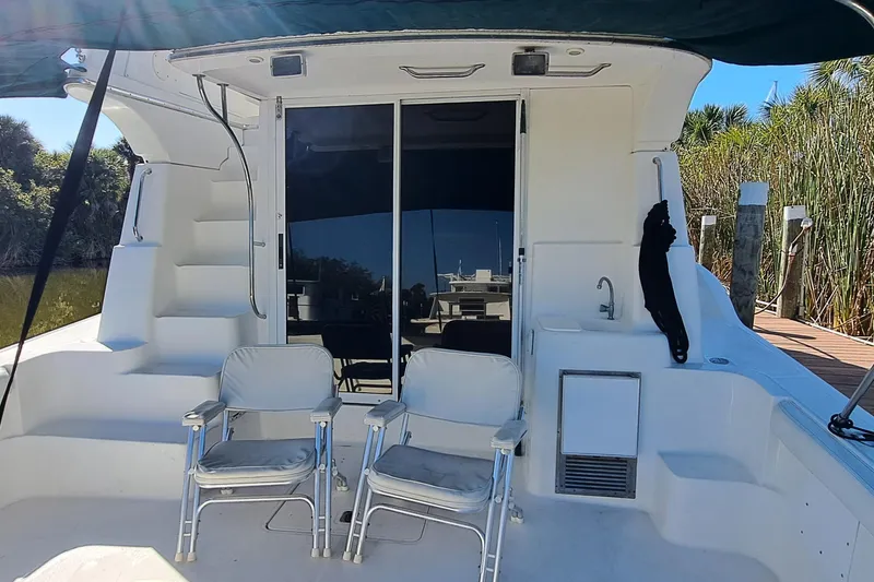 Slide: The Image of 2000 Silverton 42 Convertible yacht deck with chairs and sliding glass door. - 3