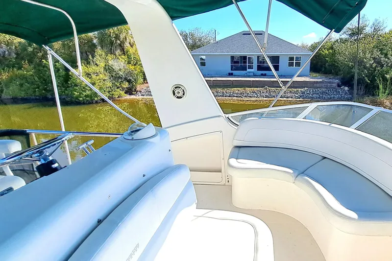 Slide: The Image of 2000 Silverton 42 Convertible yacht interior with seating, green canopy, and waterside view. - 7