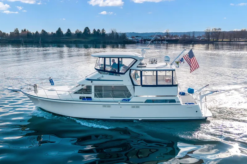 The Image of 1994 Tollycraft 45 Cockpit Motor Yacht cruising on a serene lake under a clear sky. - 1