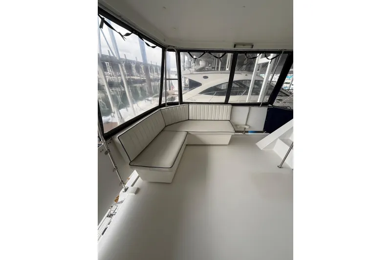 Slide: The Image of 1994 Tollycraft 45 Cockpit Motor Yacht interior with white seating and marina view. - 24