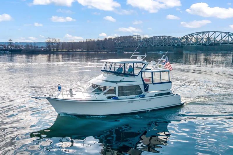 Slide: The Image of 1994 Tollycraft 45 Cockpit Motor Yacht cruising on a scenic river with bridge backdrop. - 3