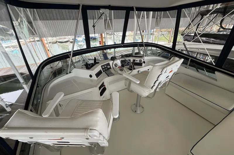 Slide: The Image of 1994 Tollycraft 45 Cockpit Motor Yacht helm with white seating and panoramic windows. - 30