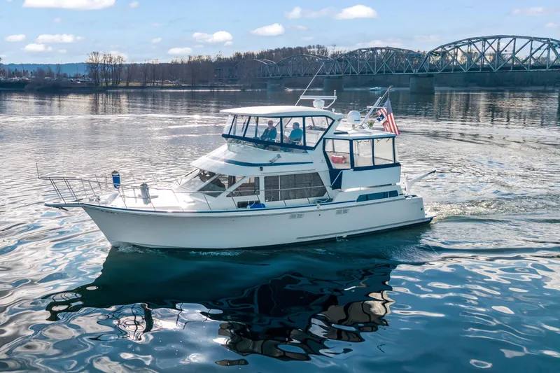 Slide: The Image of 1994 Tollycraft 45 Cockpit Motor Yacht cruising on a scenic river with a bridge backdrop. - 4