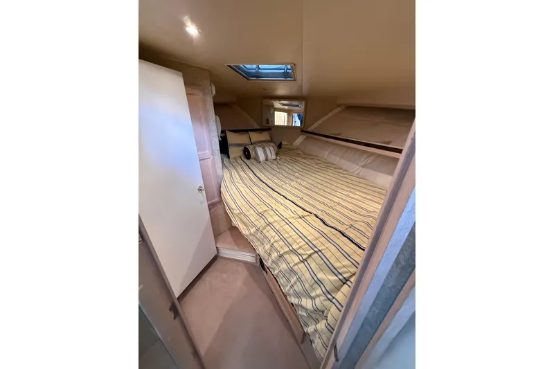 Slide: The Image of 1994 Tollycraft 45 Cockpit Motor Yacht cabin with striped bedding and skylight. - 51