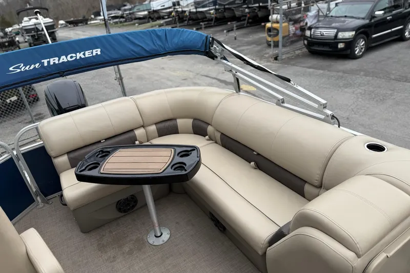 Slide: The Image of 2020 Sun Tracker Party Barge 20 DLX with beige seating and table, parked outdoors. - 8