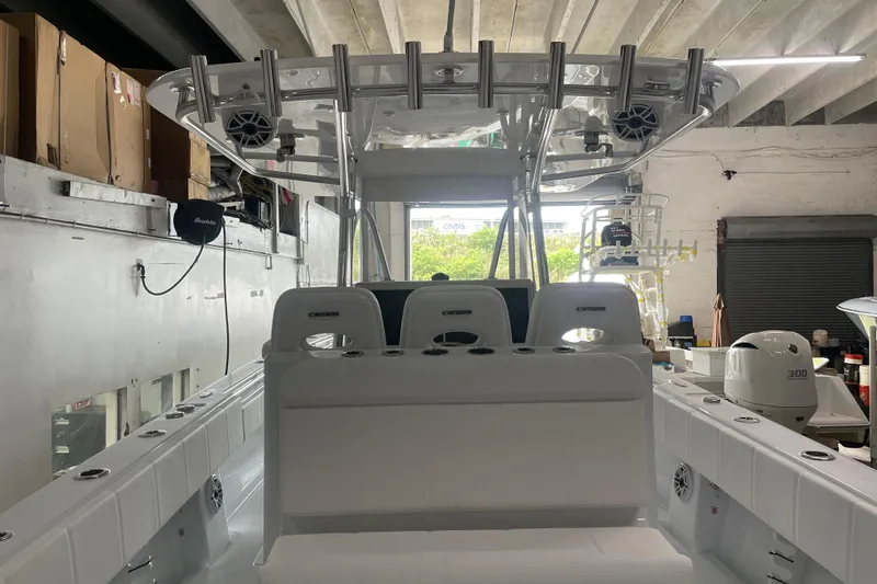 Slide: The Image of 2024 Contender 39 ST boat with rod holders and speakers, docked under a blue sky. - 14