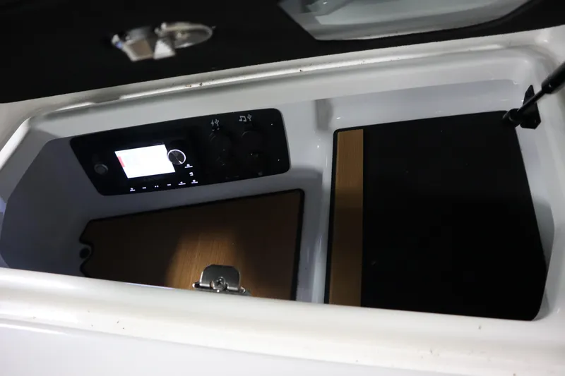Slide: The Image of 2023 Nautique Super Air Nautique G23 storage compartment with control panel and wooden accents. - 15